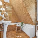Badezimmer mit sechseckigen Fliesen, weißer Waschbecken und Badewanne unter Dachschrägen.