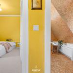 Schlafzimmer mit gelben Wänden und weißem Bett. Neben dem Bad mit Mosaikwand.