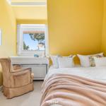 Schlafzimmer mit gelben Wänden, Bett, Schreibtisch und Sessel.