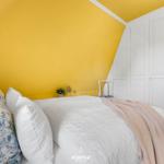 Schlafzimmer mit gelber Wand, weißem Bett und Kleiderschrank