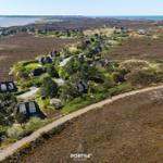Aerial view of holiday homes on heathland near the sea.