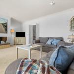 Wohnzimmer mit Sofa, Couchtisch und Kamin. An der Wand hängt ein Bild.