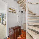 Spiralstiege mit Seilgeländer führt zu einer Wohnung mit Blick auf Garten und Terrasse.