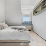 Schlafzimmer mit Bett, Fensterbank und Wandregal.