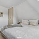 Schlafzimmer mit Dachschrägen, Bett, Kleiderschrank und Spiegel an der Wand.