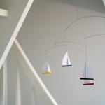 An der Wand hängt ein mobile mit Segelbooten.