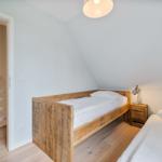 Zimmer mit zwei Betten, Holzboden und Treppe im Hintergrund.