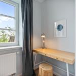 Schreibtisch mit Stuhl und Lampe neben Fenster mit Blick auf Landschaft.
