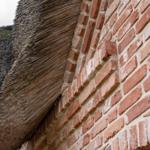 Roter Ziegelsteinmauer mit strohgedecktem Dach