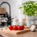 Küchenarbeitsfläche mit Tomaten, Basilikum und Gewürzgläsern