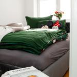 Doppelbett mit grünem Bettbezug und Minnie-Mouse-Kissen. Auf dem Bett liegen Zeitschriften.