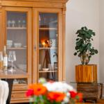 Holzschrank mit Geschirr, Pflanze in Holztopf und gedeckter Tisch