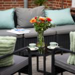 Terrasse mit Sitzgruppe, Blumen und Tassen auf Tisch