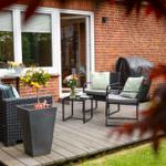 Terrasse mit Sitzgruppe, Pflanzen und Gartentisch vor rotem Backsteinhaus
