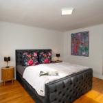 Schlafzimmer mit großem Bett, Holzboden und Wandbildern.