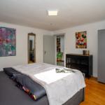 Schlafzimmer mit Bett, Kleiderschrank und Wandbildern