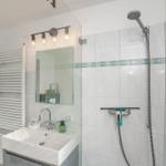 Badezimmer mit Dusche, Waschbecken und Spiegel