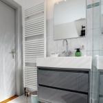 Badezimmer mit Waschbecken, Spiegel und Heizkörper