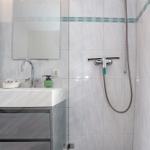 Badezimmer mit Dusche, Waschbecken und Spiegel