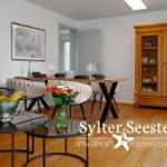Wohn- und Essbereich mit Holzboden, Sofa, Esstisch und Sideboard.