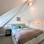 Schlafzimmer mit Dachschräge, Bett, Kleiderschrank und Nachttisch.