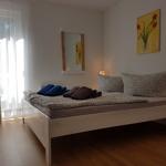 Schlafzimmer mit weißem Bett, Wandbild und Fenster mit Vorhängen.
