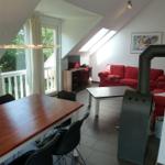 Wohn- und Essbereich mit rotem Sofa, Esstisch und Dachfenster.