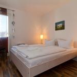 Schlafzimmer mit Bett, Nachttisch und Fenster mit Vorhang.