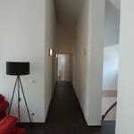 Flur mit rotem Sofa, Stehlampe und Treppe zur oberen Etage.