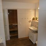 Badezimmer mit Dusche, Waschbecken und Sauna.