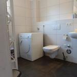 Badezimmer mit Waschmaschine, Toilette und Waschbecken.