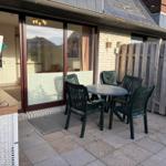 Terrasse mit Tisch und Stühlen, Sicht in Wohnraum über Glastür.