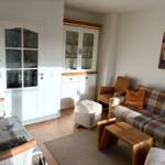 Wohnzimmer mit Sofa, Sitzgelegenheit und Glasvitrine.