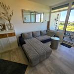 Wohnzimmer mit Sofa, Sideboard und Balkonblick