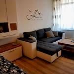 Gemütlicher Wohnbereich mit Sofa, TV und heller Wohlfühlatmosphäre für entspannte Urlaubstage.