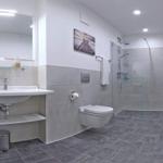 Badezimmer mit Dusche, Waschbecken und Toilette. Fliesenboden und Wandgestaltung.