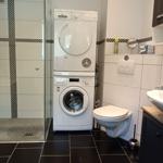 Badezimmer mit begehbarer Dusche, Badewanne, Waschmaschine und Trockner und Zugang zum Balkon
