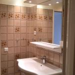 Badezimmer mit Spiegel, Waschbecken und floralen Fliesen.