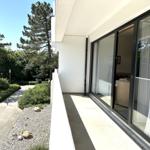 Terrasse mit Glasfront und Blick auf Grünflächen und Bäume.