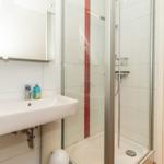 Badezimmer mit Dusche, Waschbecken und Spiegel