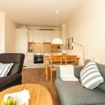 Wohnung mit Küche, Essbereich und Wohnzimmer. Möbel sind grau und holzfarben.