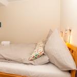 Schlafzimmer mit Bett, Kissen, Handtüchern und Wandbildern.