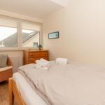 Schlafzimmer mit Bett, Nachttisch, Stuhl und Fenster.