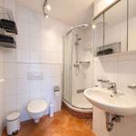 Badezimmer mit Dusche, Waschbecken und Toilette. Fliesenboden und Spiegelschrank.