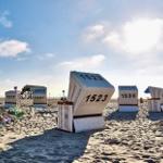 Strand mit traditionellen Strandkörben, einige stehend, einer umgekippt.