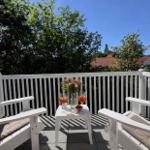 Terrasse mit zwei weißen Stühlen, Tisch und Getränken. Blick auf Bäume und Dächer.