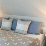 Schlafzimmer mit Bett, Kissen und Nachttischen mit Lampen.