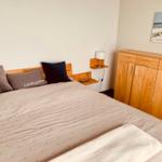 Schlafzimmer mit Bett, Nachttisch und Kleiderschrank. Wandbild zeigt Strand.