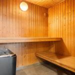 Sauna with wooden walls, bench, and stone container.