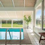 Indoor pool with wooden ceiling and large windows to the garden